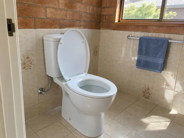 Clean white toilet in a tiled bathroom with window and towel rail in Rouse Hill